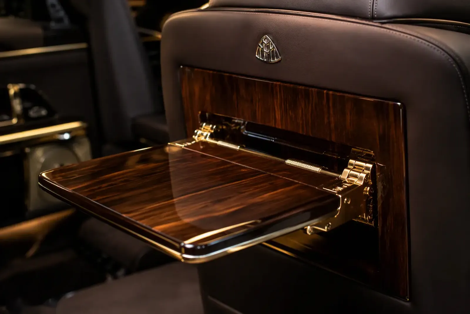 Folding polished-wood table deploying from a leather seatback — 2x3 VIP van layout Dubai